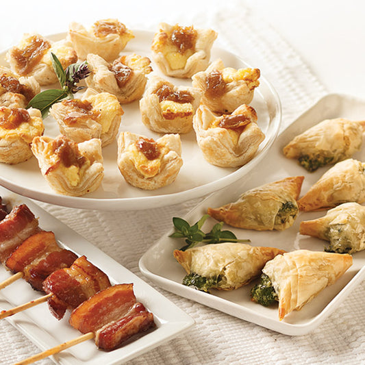 Top Rated Appetizer Sampler, featuring Vanilla-Bourbon Bacon Lollipops, Caramelized Onion & Feta Pastry Blossoms, and Spanakopita.